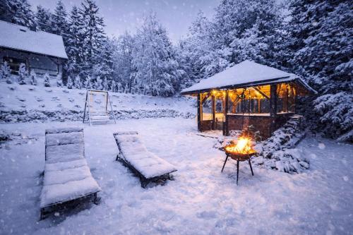 een met sneeuw bedekte tuin met een tent en een vuur bij Biały Domek Świerczek in Słopnice