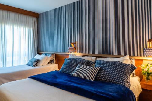 een slaapkamer met 2 bedden en een blauwe muur bij Serra Alta Hotel in São Bento do Sul