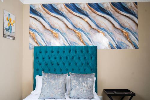 a bedroom with a blue headboard and a painting at Chic Alberton in Alberton