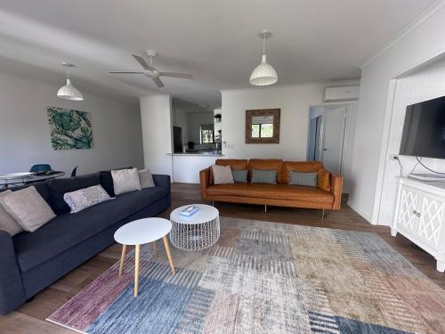 ein Wohnzimmer mit Sofa und Tisch in der Unterkunft Endless Summer 2BR Apartment with Private Beach in Noosa Heads