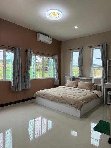 a bedroom with a large bed and windows at บ้านไร่สกายดาว in Pak Chong