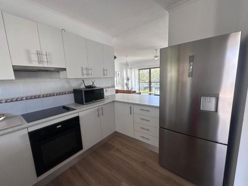 eine Küche mit weißen Schränken und einem Edelstahlkühlschrank in der Unterkunft Endless Summer 2BR Apartment with Private Beach in Noosa Heads