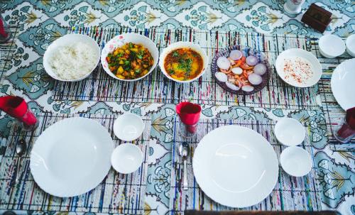 una tavola ricoperta di piatti e ciotole bianchi di The River Trail Cottage by The StayCationer a Rājpur