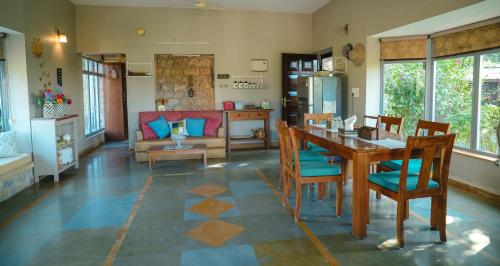 un soggiorno con un tavolo e un divano di The River Trail Cottage by The StayCationer a Rājpur