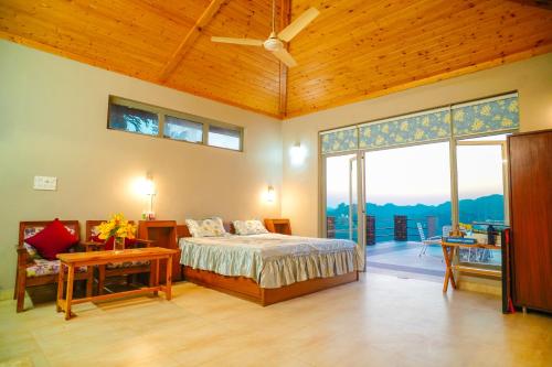 una camera da letto con un letto e una grande finestra di The River Trail Cottage by The StayCationer a Rājpur