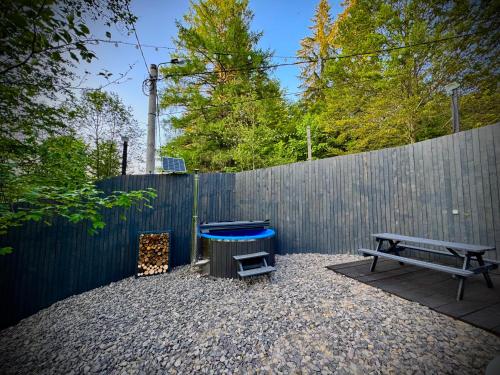 een achtertuin met een bankje, een barbecue en een hek bij M Cabin A Frame Predeal 2 Ciubar in Predeal