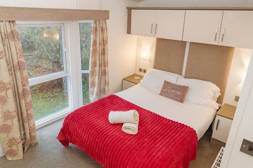 a bedroom with a bed with a red blanket and a window at Chloe Cabin in West Thirston