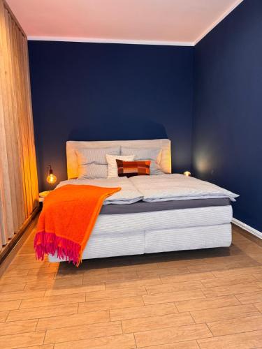 a blue bedroom with a large bed with an orange blanket at Ferienwohnung Erfurter Seen - Nöda 2 in Nöda