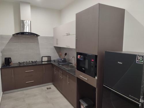 eine Küche mit braunen Schränken und einem schwarzen Kühlschrank in der Unterkunft Sky Park Nest in Islamabad