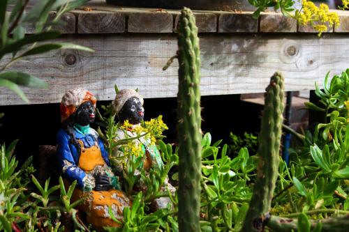 two statues sitting in a garden in front of a house at Sirena Insolente Hostel & Suites in Pichilemu