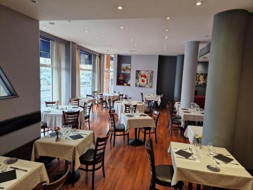 ein Esszimmer mit weißen Tischen und Stühlen in der Unterkunft Hotel Restaurant l'Amandois in Saint-Amand-Montrond