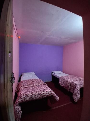 two beds in a room with pink and purple walls at Kimche Guest House in Astam