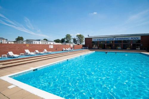 een groot zwembad met stoelen en een gebouw bij Suntrail House in Great Clacton