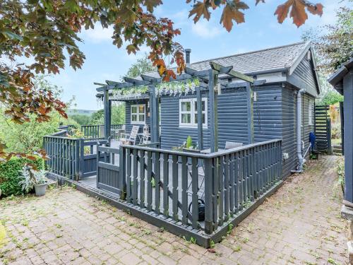 a blue house with a porch and a fence at Hygge Cabin in Hexham