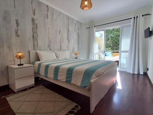 een slaapkamer met een bed en een groot raam bij Refugio Madeira in Caniço