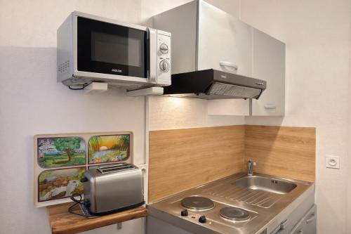 a small kitchen with a sink and a microwave at Le Retro Gaming - Le Havre Train Station in Le Havre