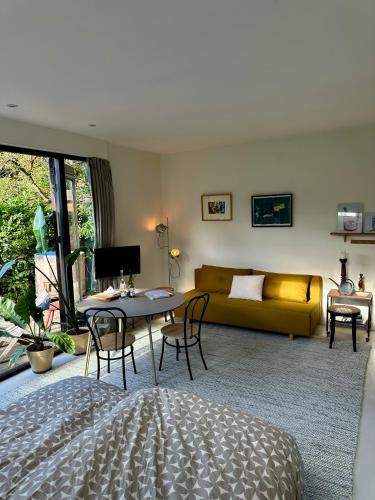 a living room with a yellow couch and a table at Garden Guest house & Sauna in Deventer