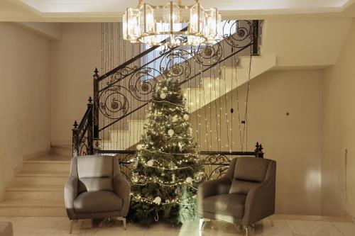 a christmas tree in a living room with two chairs at Phazisi Hotel in Tbilisi City