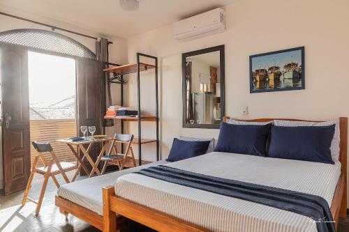 a bedroom with a bed and a table and a window at APART STUDIOS PONTAL in Ilhéus