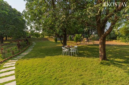 a table and chairs in a park under a tree at EKOSTAY - Brick Wood in Karjat