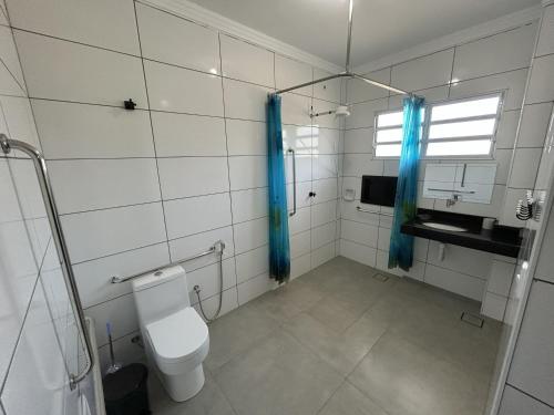 a bathroom with a toilet and blue shower curtains at Recanto Ubaduba in Ubatuba