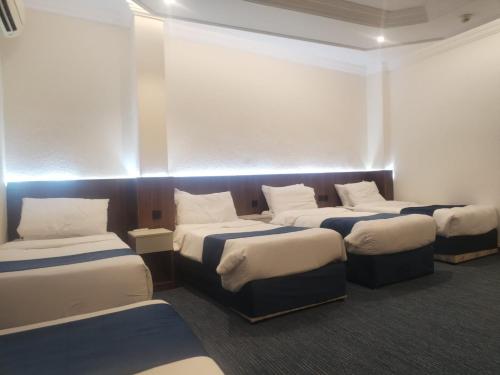 Habitación con 4 camas y luces. en Zwar Alharam Makkah Hotel, en La Meca