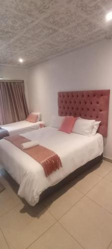 a bedroom with two beds and a headboard at Lifegate Guesthouse in Johannesburg