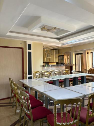 une pièce avec des tables et des chaises et une cuisine dans l'établissement H-KREMLIN srl, à Yaoundé