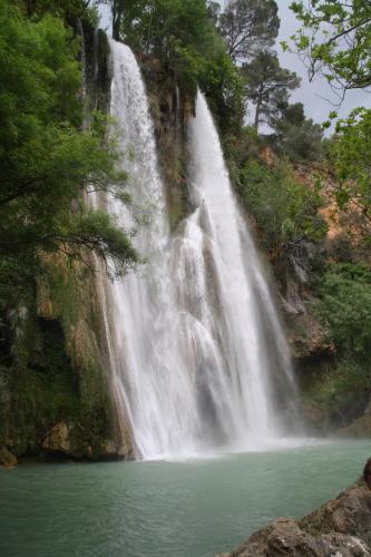 a waterfall with a pool of water in front of it at Campagne de la source St Martin B&B in Cotignac