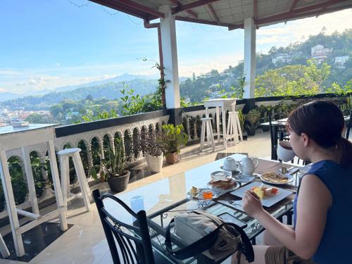 eine Frau, die mit einem Teller Essen an einem Tisch sitzt in der Unterkunft Mount Palace in Kandy