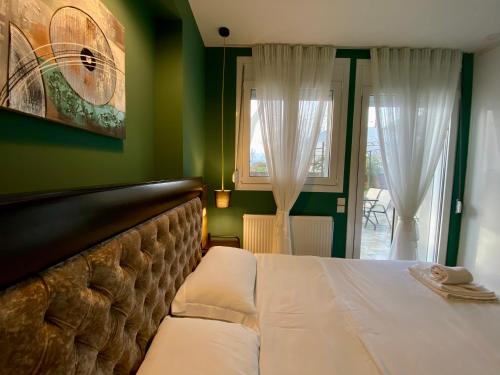 a bedroom with a white bed with green walls and windows at LUX ONE The Ioannina Residence in Ioannina