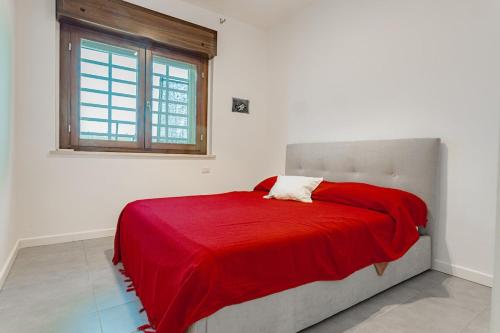 a bedroom with a bed with a red blanket on it at La casa di Plinio in Infernetto
