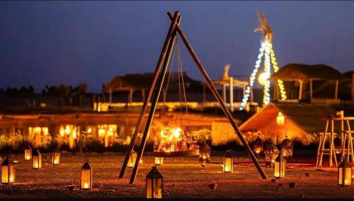 een groep lichtjes en een vuur in een veld 's nachts bij Agafay Private evening camel ride sunset dinner show private experience in Marrakesh