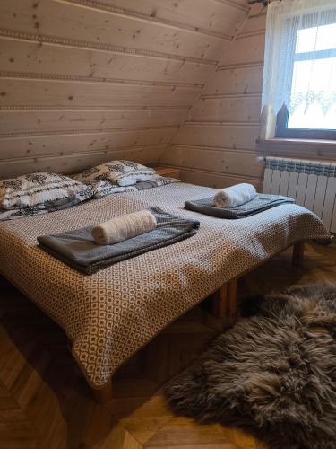 two beds in a wooden room with towels on them at Apartamenty HAWOK in Groń