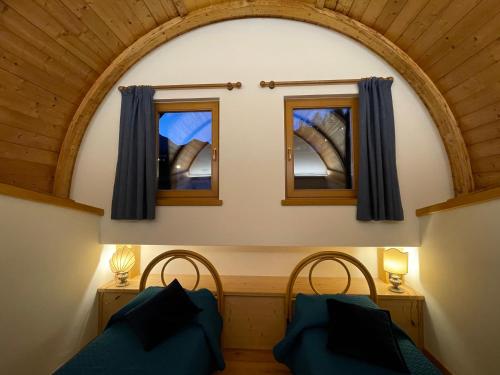 een kamer met 2 bedden en 2 ramen bij Luna Rossa Dolomiti in Domegge di Cadore