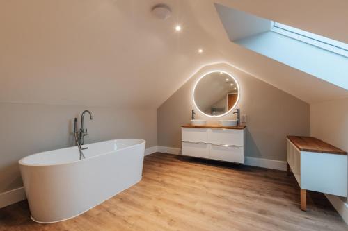 a bathroom with a large white tub and a window at The Stables - Newly Renovated 4 bed house in Catworth