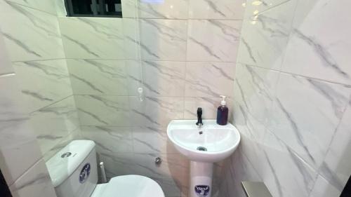 um banheiro branco com uma pia e um vaso sanitário em Deluxe One Bedroom Apartment em Ikeja
