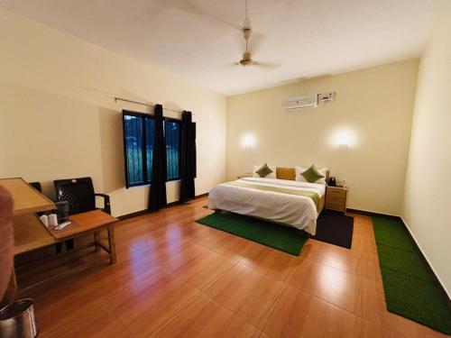 a bedroom with a bed and a table and a desk at Jim Corbett Guest House in Jhirna