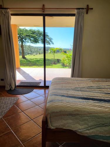 um quarto com uma cama e uma janela grande em Hacienda en Los Volcanes em Guayabos