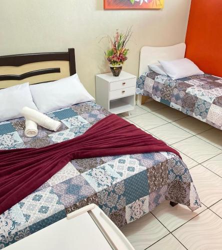 una camera con due letti e un comodino con una pianta di Pousada Novo Amanhecer a Itarema