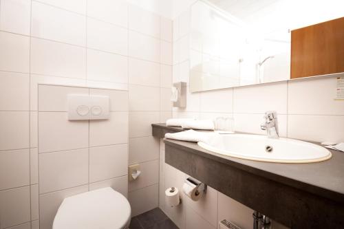 a white bathroom with a sink and a toilet at Wohlfühlhotel DER JÄGERHOF in Willebadessen