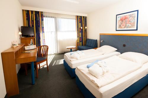 a hotel room with two beds and a desk at Wohlfühlhotel DER JÄGERHOF in Willebadessen