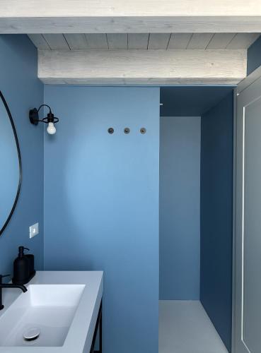 ein Badezimmer mit einem weißen Waschbecken und einer blauen Wand in der Unterkunft Tarsilla Appartamenti - Centro Storico in Caorle