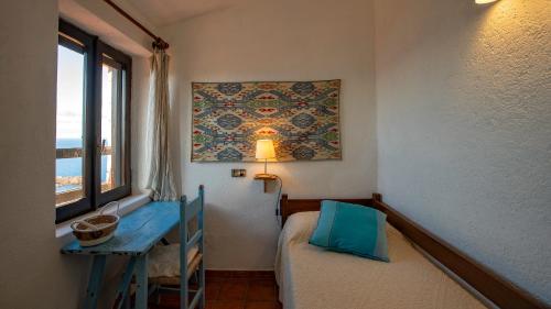 a small room with a bed and a table and a window at Casa Cielo Mare in Costa Paradiso
