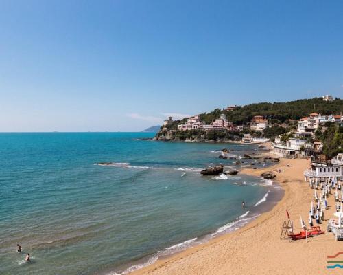 a beach with a group of people and the ocean at La Casetta in Rosignano Marittimo