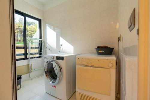 eine Waschmaschine und einen Trockner in einem Zimmer mit Fenster in der Unterkunft Design Gardens Nº2 in Bicas