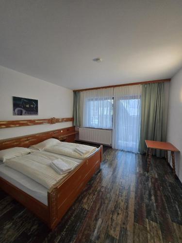 a bedroom with a bed and a table in it at Hotel Haus Kärnten in Bad Bleiberg