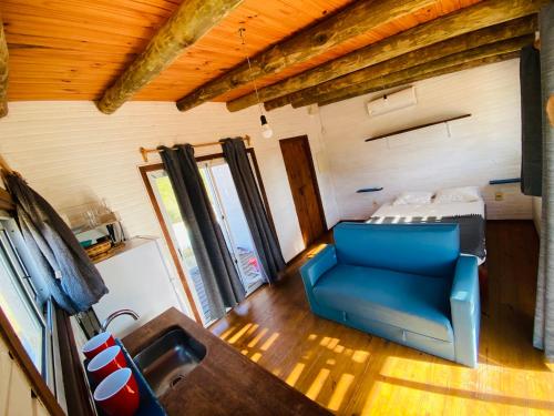 a living room with a blue chair and a bed at La Fresa glamping in Punta Del Diablo