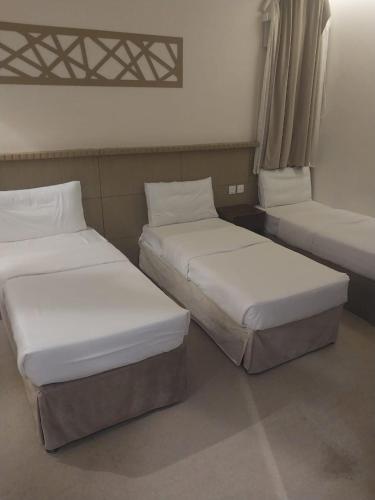 deux lits côte à côte dans une pièce dans l'établissement فندق الرسالةالذهبي شارع ام القري, à Aş Şafā