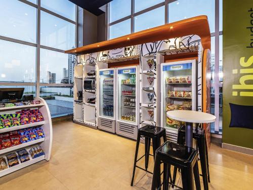 a store with two refrigerators and a table and stools at Ibis Budget Fortaleza Praia de Iracema in Fortaleza